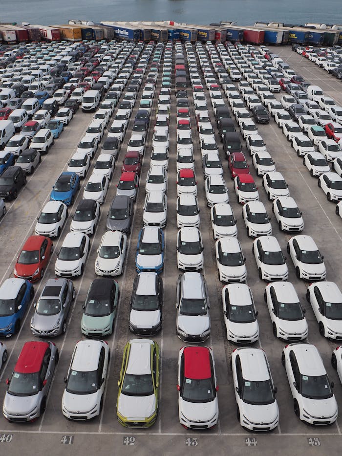 Top-down view of a large parking lot with rows of cars in Barcelona's port area.